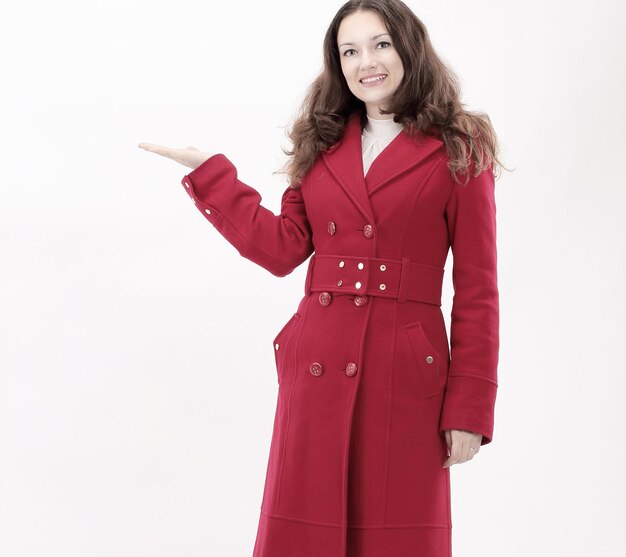 Smiling young woman in red coat showing on copy space