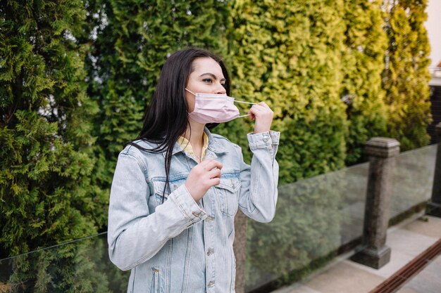 Smiling young woman removes medical mask from face termination\
of quarantine coronavirus woman protecting from coronavirus covid19\
happy time fresh air