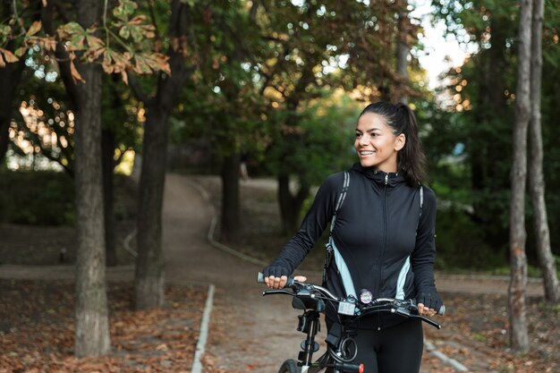 公園で自転車に乗って笑顔の若い女性