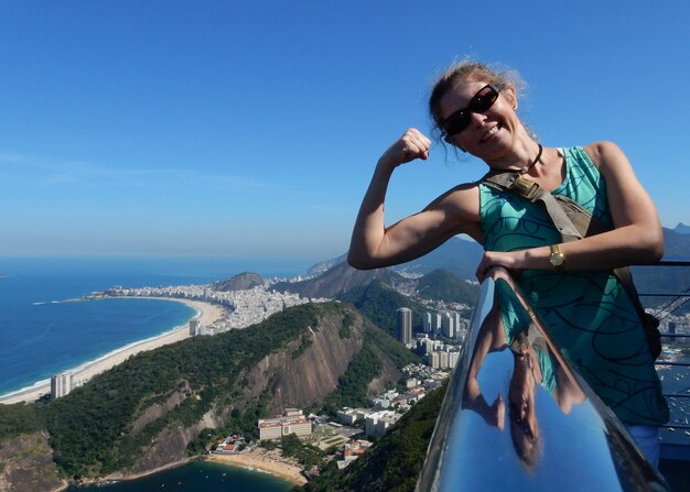 Photo smiling young woman showing bicep at observation point