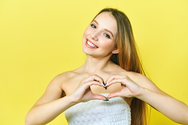 smiling young woman showing heart shape hand sign