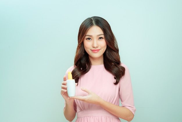 Smiling young woman showing skincare products