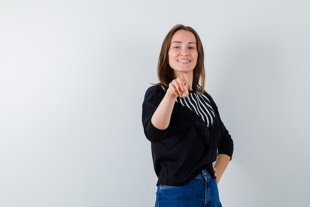 Smiling young woman showing something with her finger on white background