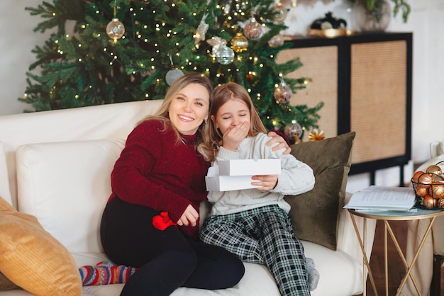 Photo smiling young woman sitting by christmas tree