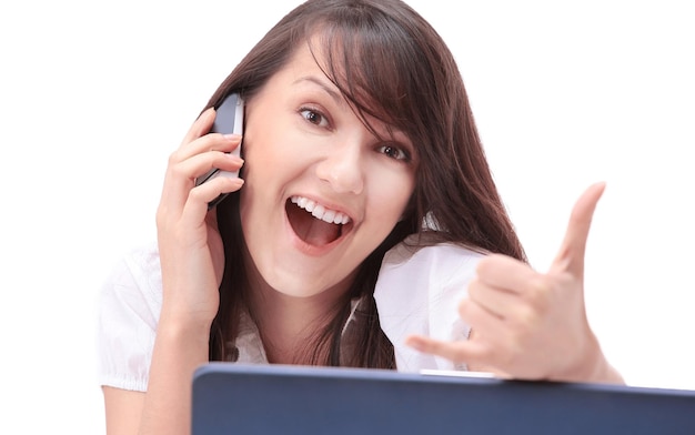 Smiling young woman sitting behind a Desk and showing thumb up