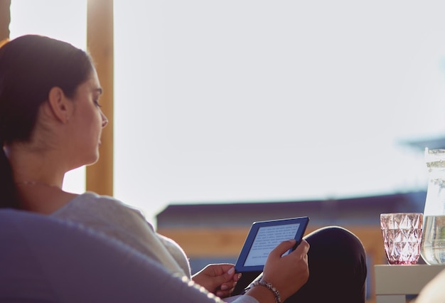 Smiling young woman sitting on sofa with touchpad