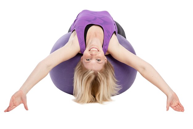 Smiling young woman in sportswear doing exercises with fitness ball. Isolated over white background.