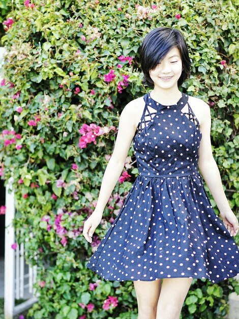 Smiling young woman standing against plants