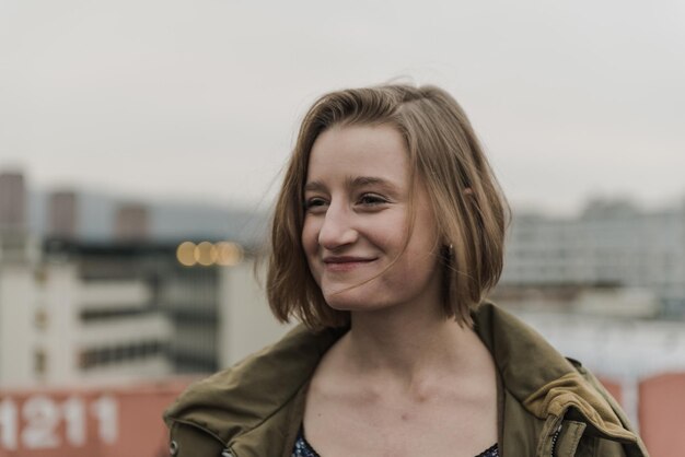 Foto una giovane donna sorridente in piedi contro il cielo durante il tramonto