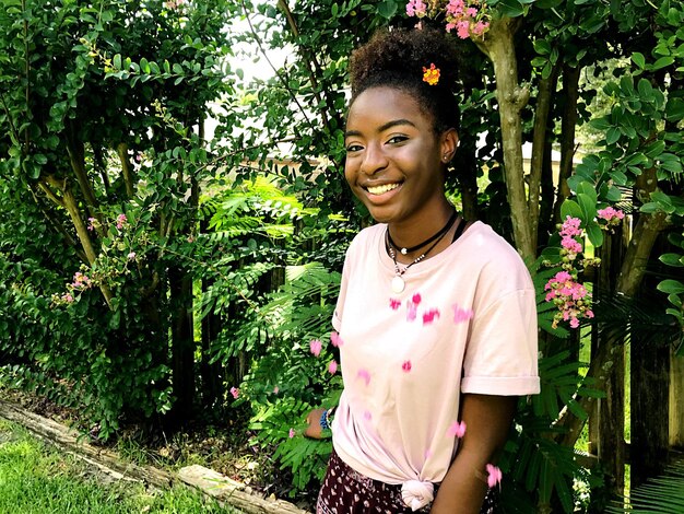 Smiling young woman standing against trees at park