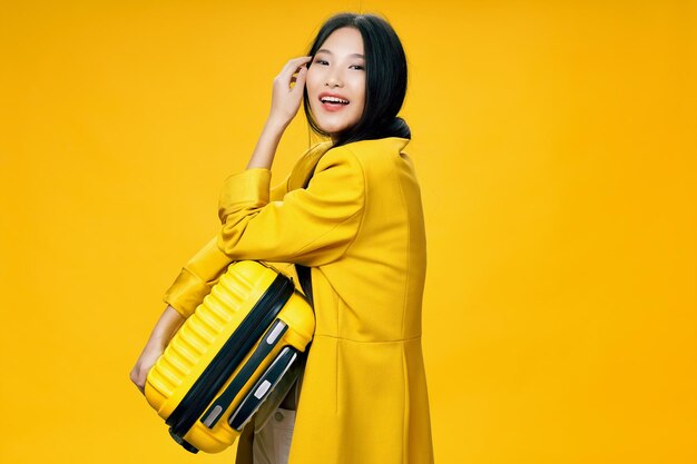 Smiling young woman standing against yellow background