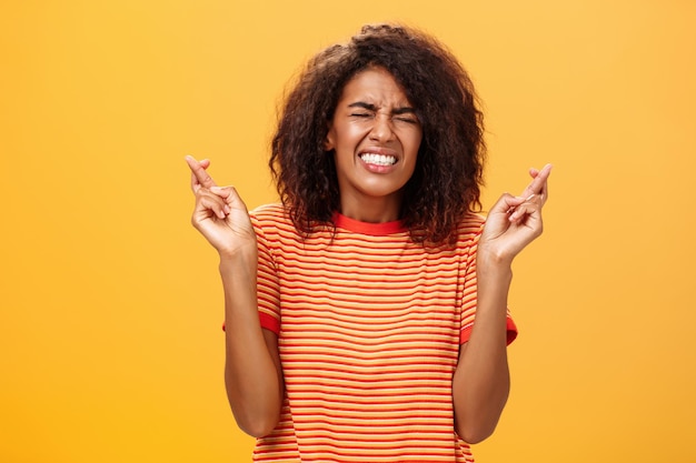 Smiling young woman standing against yellow background