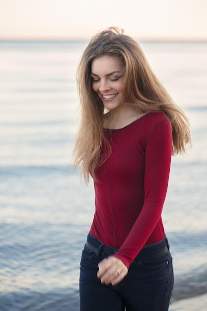 Photo smiling young woman standing at beach