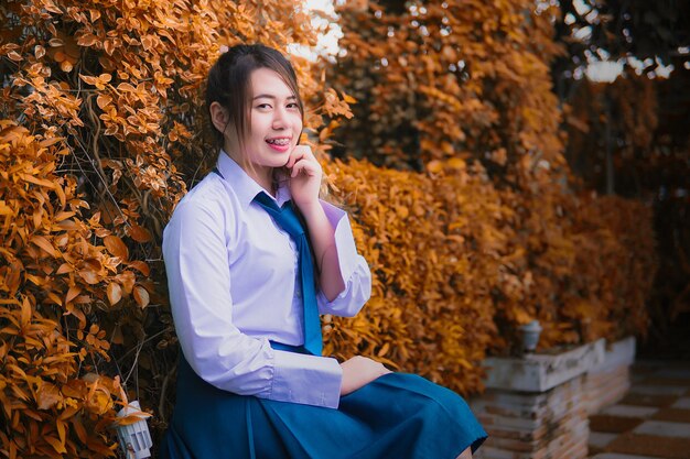 Smiling young woman standing by tree during autumn