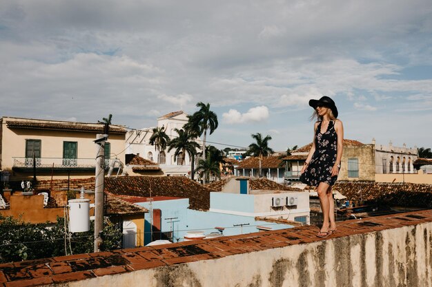 Photo smiling young woman standing on wall against cloudy sky