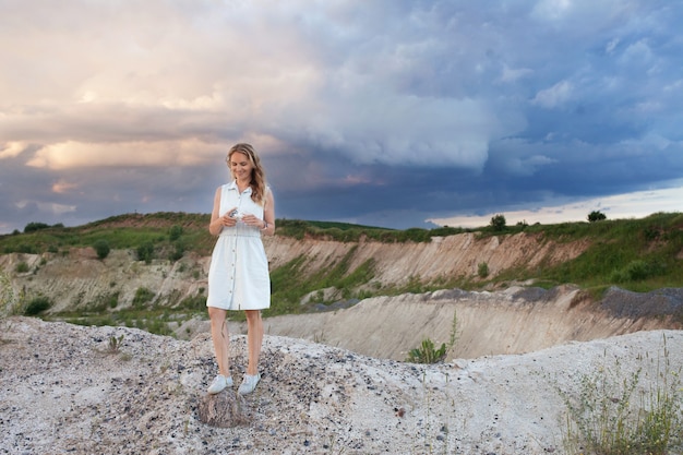 Smiling young woman staying  at background of  natural landscape with hills and thunderstorm clouds.