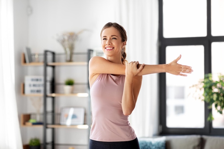 Photo smiling young woman stretching arm at home