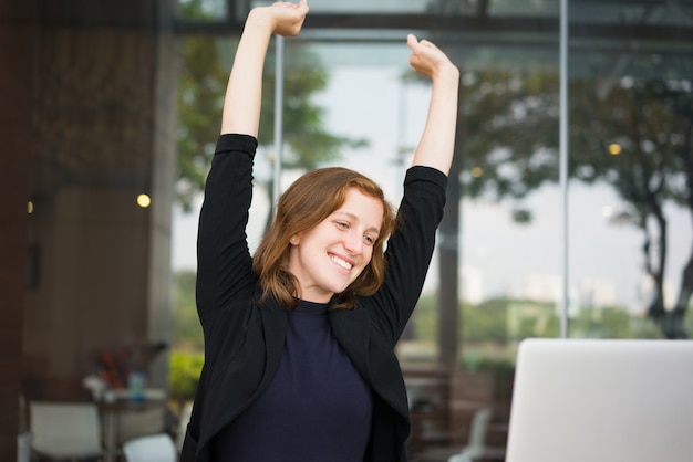 Smiling Young Woman Stretching in Cafe