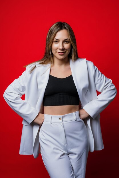 A smiling young woman in a stylish white suit on a red background Business portrait of a freelancer