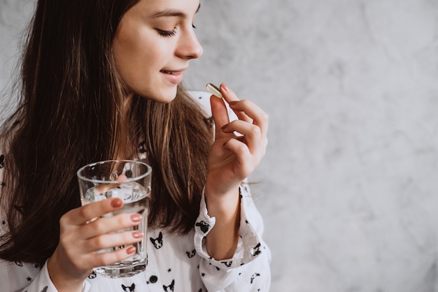 写真 水で薬を飲んで笑顔の若い女性