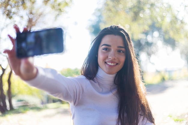 写真 携帯電話からセルフィーを撮る笑顔の若い女性