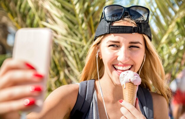 Photo smiling young woman taking selfie while eating ice cream