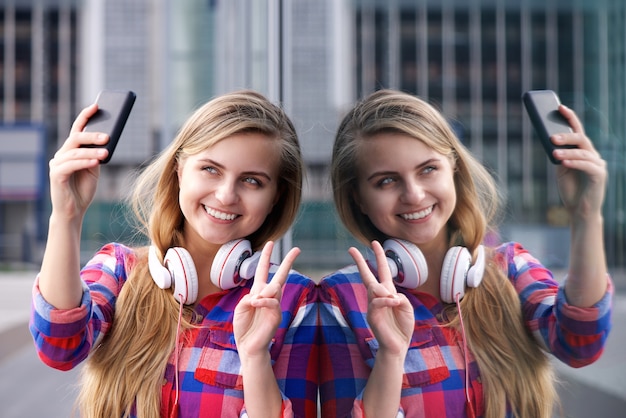 Smiling young woman taking selfie with peace hand sign