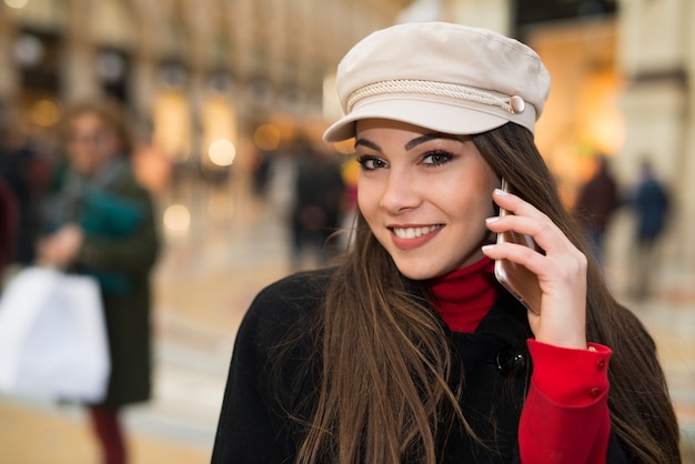 Улыбающаяся молодая женщина разговаривает по мобильному телефону