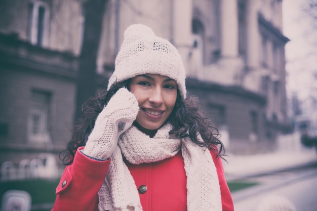 Smiling young woman talking on mobile phone outdoors during winter