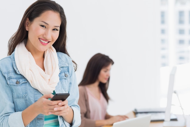 Smiling young woman text messaging in office