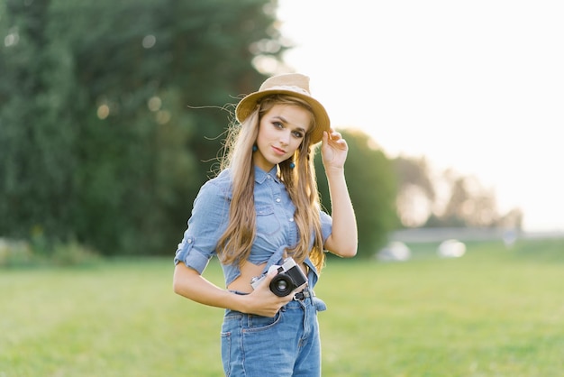 웃고 있는 젊은 여성은 여름에 공원에서 사진을 찍기 위해 카메라를 사용한다