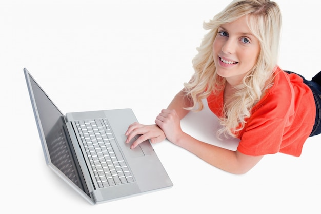 Smiling young woman using her laptop while lying down