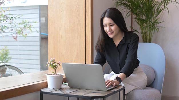 Smiling young woman using laptop shopping online or chatting online in social network