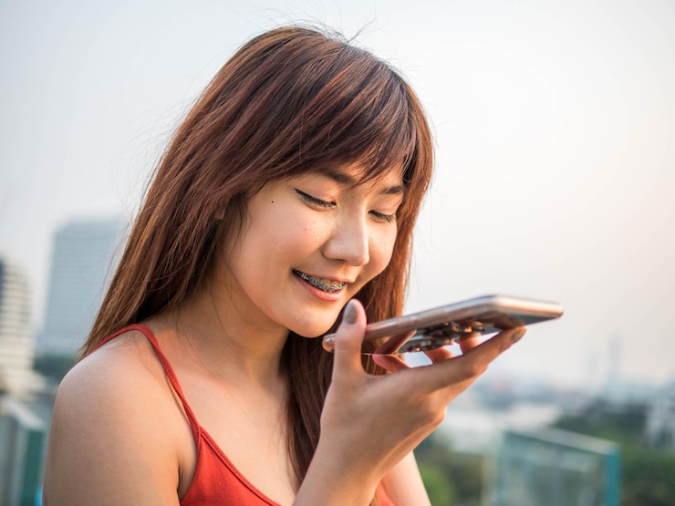 Photo 空に向かって携帯電話を使っている笑顔の若い女性