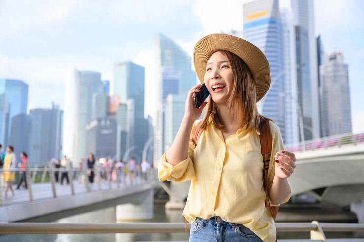 Photo 街で携帯電話を使っている笑顔の若い女性