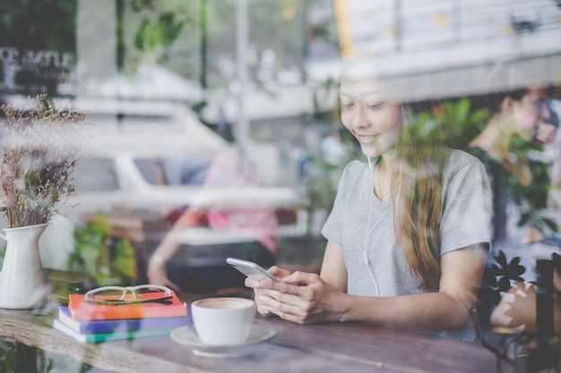 Foto giovane donna sorridente che usa il cellulare al ristorante