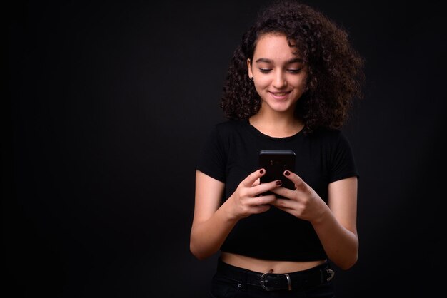 黒い背景に電話を使って微笑む若い女性