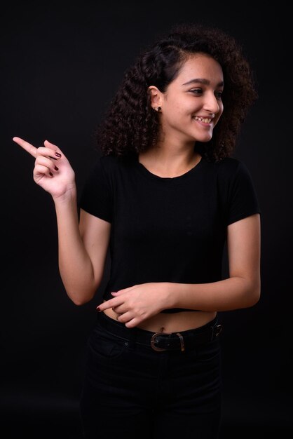 Foto giovane donna sorridente che usa uno smartphone su uno sfondo nero