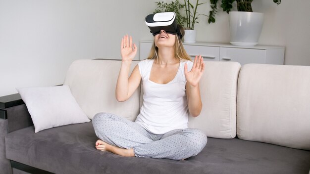 VR 고글에 웃는 젊은 여성이 웃고 비디오 시청을 즐기고 있습니다.