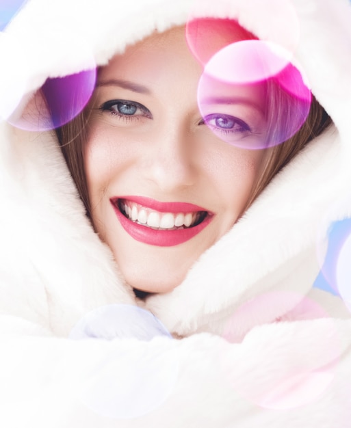 ふわふわの白い毛皮のコートを着て笑顔の若い女性