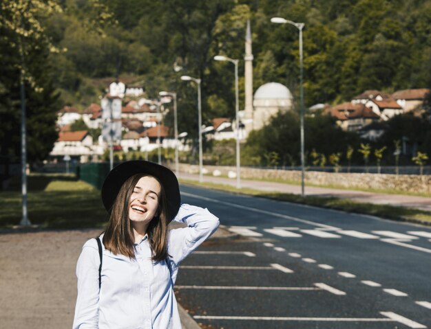 Foto una giovane donna sorridente che indossa un cappello in piedi sulla strada