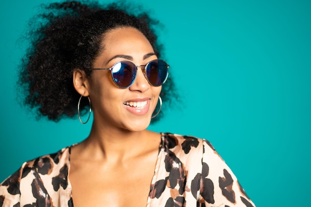 Smiling young woman wearing sunglasses against blue background