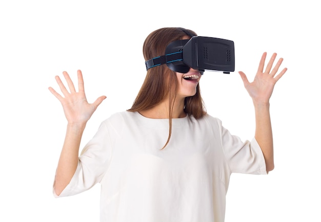 Smiling young woman in white shirt using virtual reality glasses on white background in studio