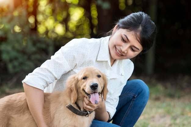 写真 公園で犬と一緒に笑顔の若い女性