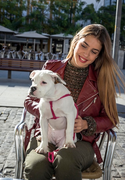 歩道の椅子に座っている犬と笑顔の若い女性