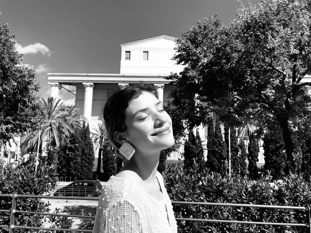 smiling young woman with eyes closed in park during sunny day