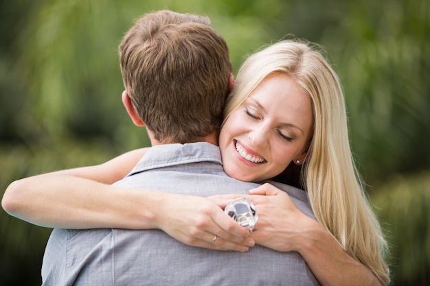 Giovane donna sorridente con gli occhi chiusi mentre abbraccia uomo