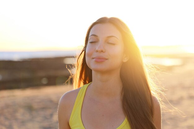 Photo smiling young woman with eyes closed while standing at beach