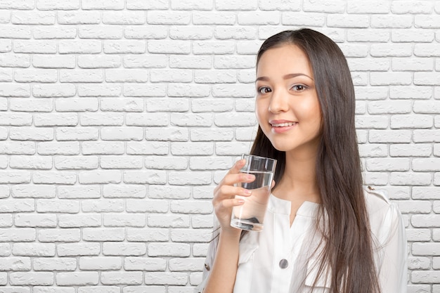 Giovane donna sorridente con bicchiere d'acqua