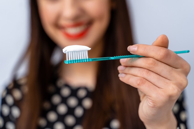 Smiling young woman with healthy teeth holds a toothbrush. Selective focus. Cropped photo.